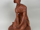 statue d'une femme assise sur un rocher, les mains posées sur les genoux
