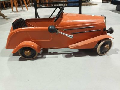 une petite voiture orange posée par terre dans une pièce