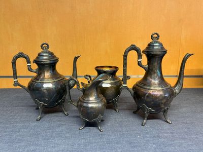 trois théières en argent et une cafetière posées sur une table
