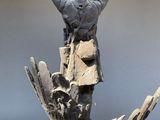 a statue of a man standing on top of a piece of wood