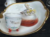 une tasse et une soucoupe posées sur une assiette sur laquelle se trouve une figurine