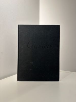 un livre noir posé sur une table à côté d'un mur blanc