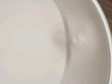 a white bowl with a handle on it sitting on a counter