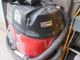 un aspirateur rouge et noir posé à côté d'une porte de garage