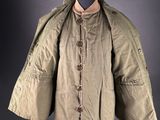 an old jacket on a mannequin stand with a black background