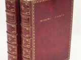 two red books with gold trims on them sitting next to each other