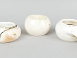 three white vases sitting on top of a table next to each other