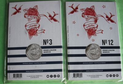two packs of silver coins with red roses on them on a green surface