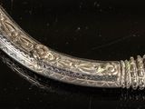 a silver object on a black surface with a black background