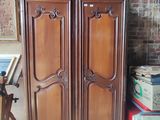 a wooden armoire in a room with a painting on the wall