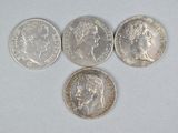 four different types of silver coins on a white surface