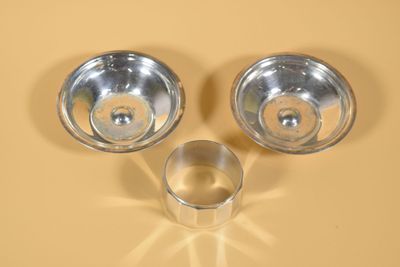 deux bols en argent et une coupe en argent posés sur un fond jaune