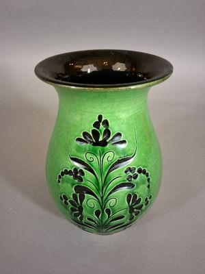 un vase vert avec un couvercle noir posé sur une table blanche
