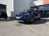 une voiture bleue garée devant un immeuble, à côté d'une caravane