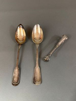 deux cuillères et un repose-cuillère posés sur une table, avec une cuillère devant chacune d'elles