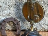 une petite horloge ancienne posée sur une table, à côté d'un fer à cheval