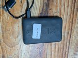 une photo d'une batterie externe noire posée sur une table en bois