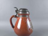 a red pitcher with a bird on it on a table