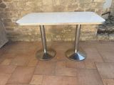 a white table with two silver legs on a brick floor