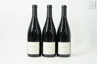 trois bouteilles de vin sont alignées sur une surface blanche