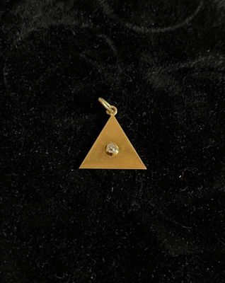 a gold triangle charm with a diamond on it