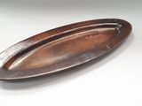 une assiette ovale marron posée sur une table, sur fond blanc