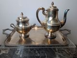 two silver teapots sitting on a tray on a table