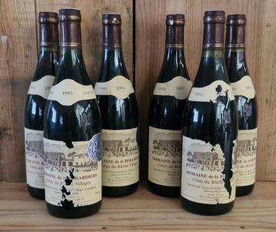 several bottles of wine are lined up on a wooden shelf