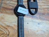 une montre connectée posée sur une table en bois à côté d'un chargeur