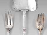 une cuillère et une fourchette en argent, ainsi qu'un repose-cuillère, posés sur une table