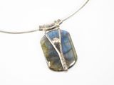 un gros plan d'un collier orné d'une pierre bleue montée sur une chaîne en argent