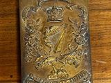 une vieille plaque en laiton posée sur une table en bois, sur laquelle figure une couronne