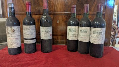 six bottles of wine are lined up on a red table cloth