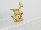 a gold figurine of a bird and a dog on a clear shelf