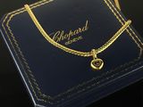 a close up of a gold necklace with a heart on it