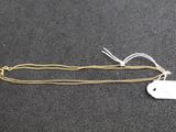 une chaîne en or à laquelle est accrochée une médaille, posée sur une surface noire
