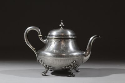 une théière ancienne en argent posée sur un socle, sur fond noir