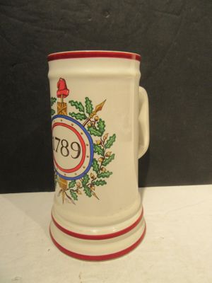 une tasse blanche avec un bord rouge et un blason dessus