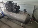 un gros compresseur d'air posé sur un réservoir métallique