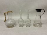 trois vases en verre et une carafe en verre posés sur une surface blanche