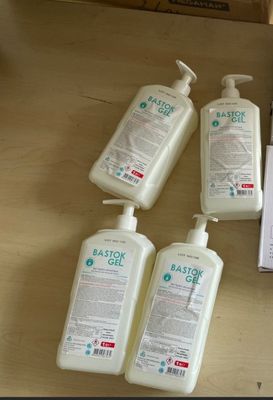plusieurs flacons de gel hydroalcoolique posés sur une table à côté d'une boîte de savon