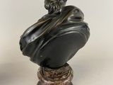 a black marble bust of a man with a hat on a pedestal