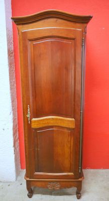 une grande armoire en bois devant un mur rouge
