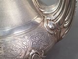 a silver tea pot with a handle on a table