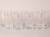six clear glasses lined up in a row on a white surface