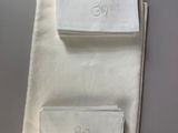three white napkins with embroidered monograms on them on a table