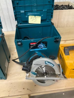 une boîte bleue contenant une scie circulaire, à côté d'une boîte à outils jaune