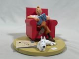 a figurine of a man sitting in a chair reading a book and a dog laying on the floor