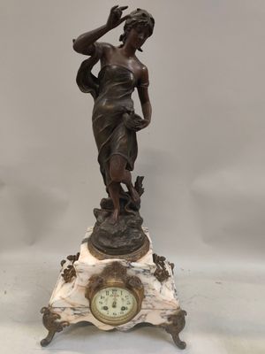 statue d'une femme tenant un oiseau sur un socle en marbre, avec une horloge au premier plan