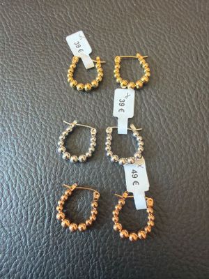 three pairs of hoop earrings and a pair of hoop earrings on a black leather surface